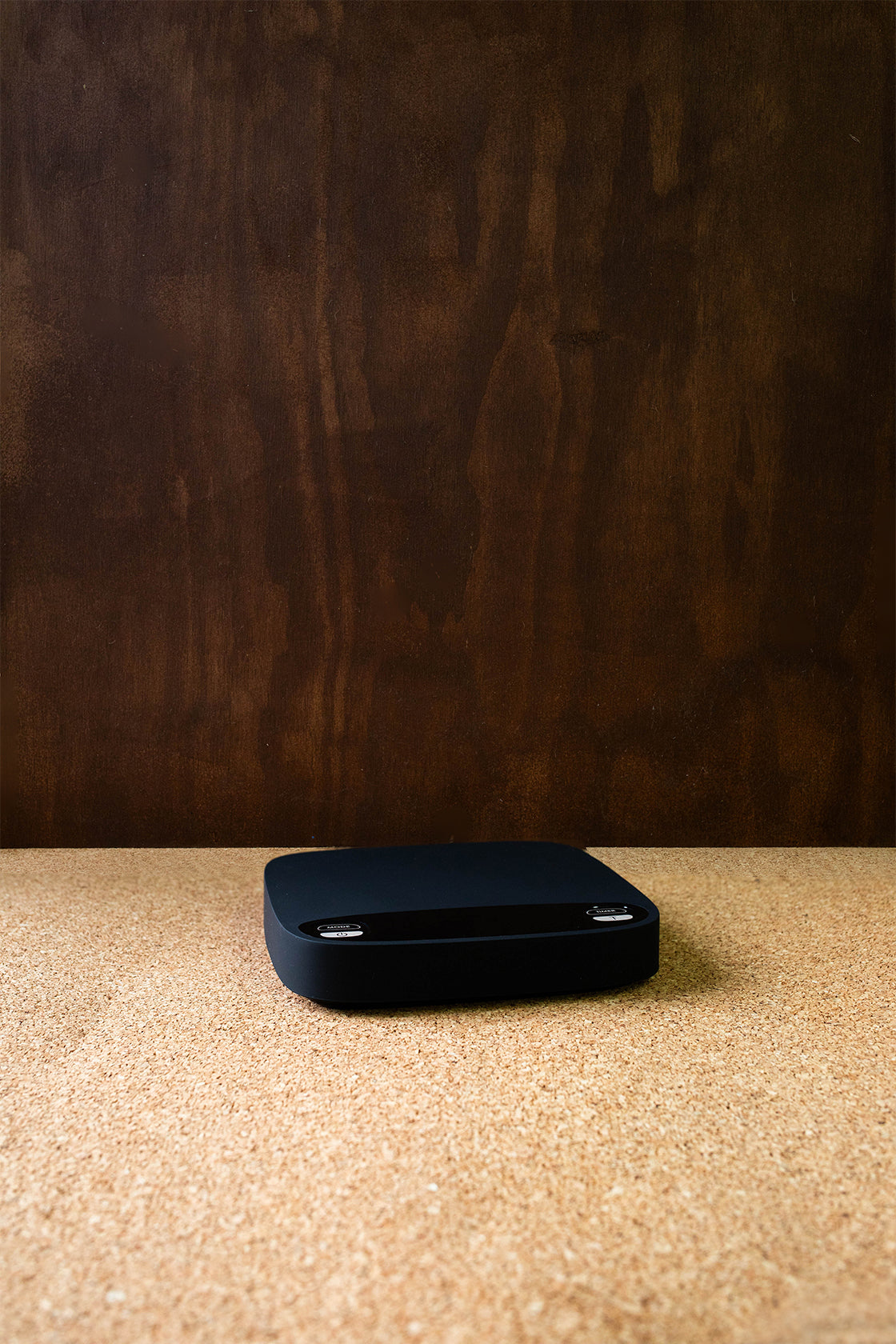 A black Brewace digital coffee scale placed on a wooden surface, displaying a clean and simple design with a large LED screen.