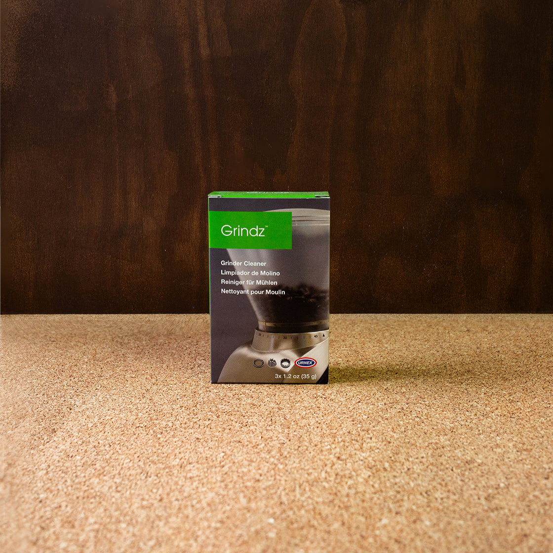A box of Urnex Grindz Grinder Cleaning Tablets placed against a wooden background.